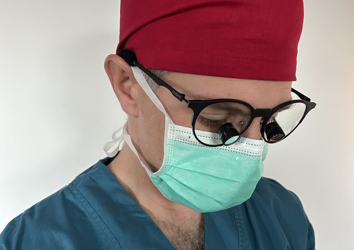 Mr Oliver Lyons wearing surgical loupes and theatre attire